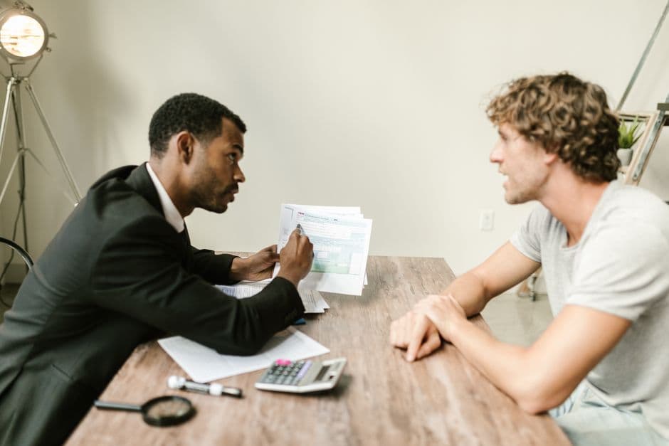 A professional showing a document to a client across a desk during a consultation