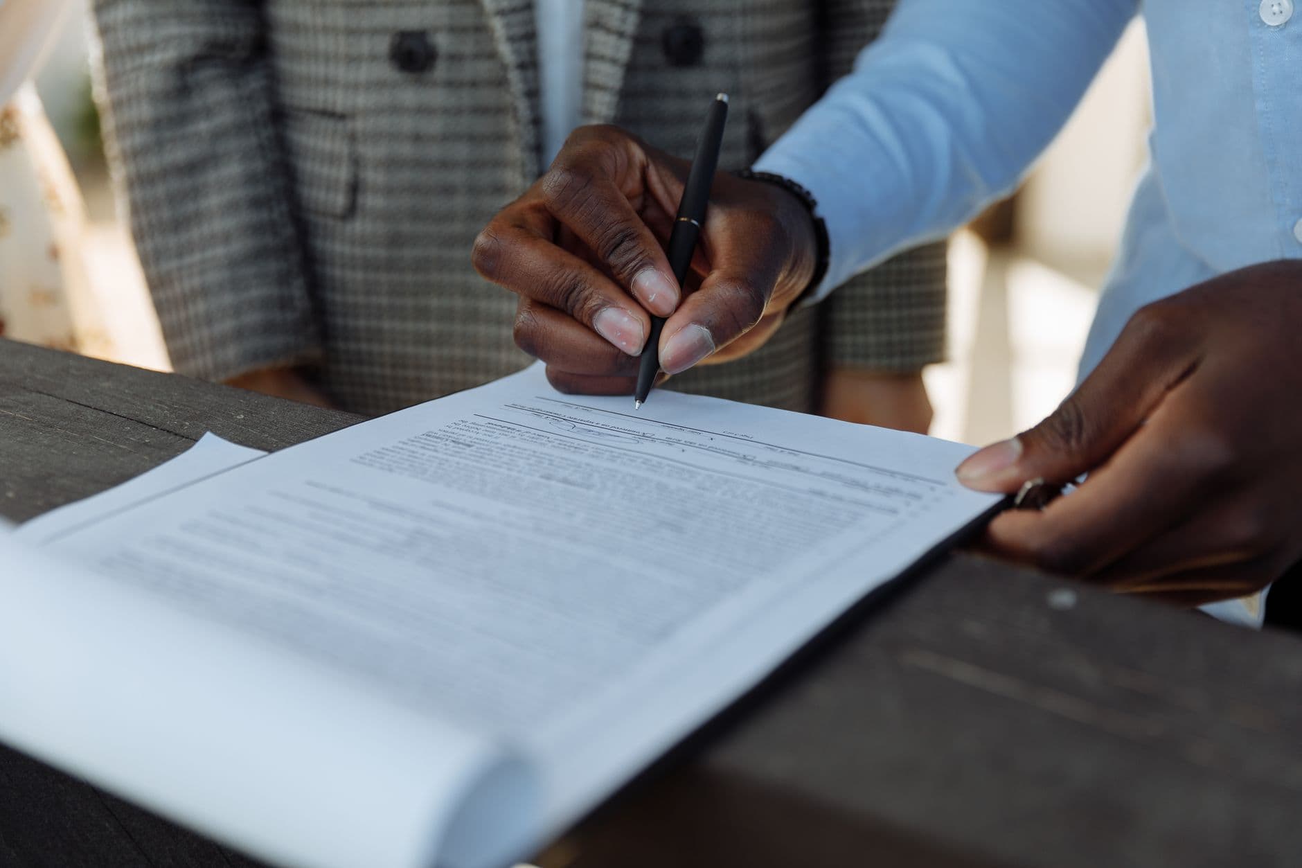 Close-up of business professionals signing a document with a pen